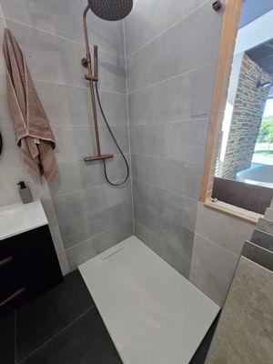 une salle de bains équipée d'une douche, d'un lavabo et d'un miroir