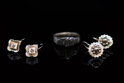three pairs of earrings and a ring on a black surface