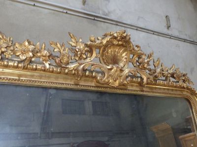 a large mirror with a gold frame on the wall