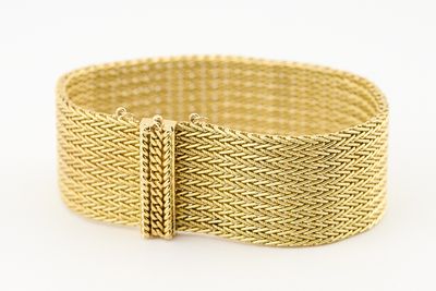 gros plan d'un bracelet en or sur fond blanc