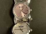two watches are sitting side by side on a black surface
