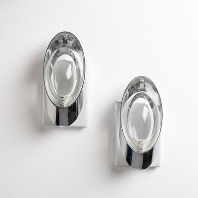 two chrome wall sconces mounted on a white wall
