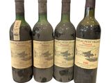 four bottles of wine are lined up on a white surface