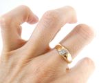 a person ' s hand with a gold and diamond ring