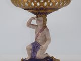 a blue and gold vase on a stand with a man on it