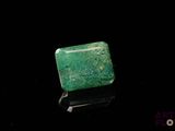 a close up of a green emerald stone on a black surface