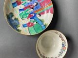 two plates and a cup on a table with a painting on them