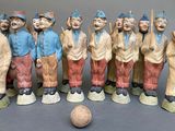 many figurines of people standing next to a ball