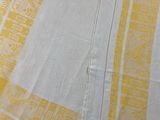 a yellow and white towel on a bed next to a pillow