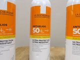 three bottles of sunscreen lotion sitting on a wooden table