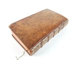 an old book is sitting on a white surface with a string
