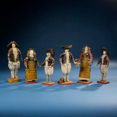 Plusieurs figurines représentant des personnes vêtues de costumes traditionnels sont alignées en rang