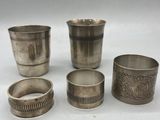 four silver cups and a napkin holder on a white surface