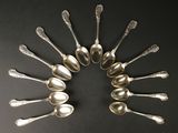 six cuillères en argent disposées en cercle sur une surface noire