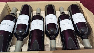 six bottles of wine are in a wooden box on a table