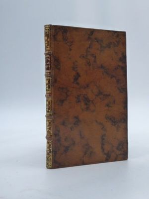 un vieux livre brun posé sur une surface blanche