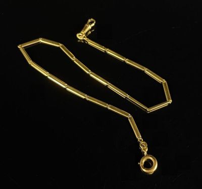 a gold necklace with a chain and a clasp on a black background