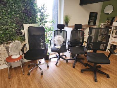 plusieurs chaises de bureau et un ventilateur dans une pièce au sol en parquet