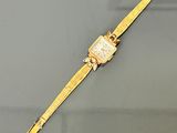 an image of a gold wrist watch on a grey surface
