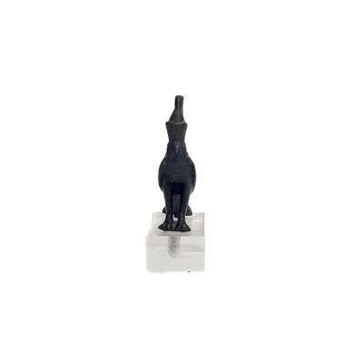 une statue noire représentant un chat assis sur une surface blanche