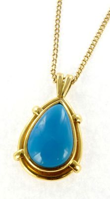 un collier en or orné d'une pierre bleue en forme de larme, monté sur une chaîne