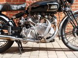 a black motorcycle parked next to a brick wall