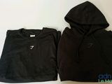 a black hoodie and a black cropped top sitting on top of a white table