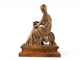 bronze statue of a woman sitting on a bench with a book