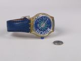 montre-bracelet avec un bracelet en cuir bleu, un boîtier doré et une pièce de monnaie