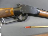 a rifle that is laying on a table next to a pencil