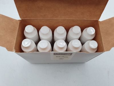 six bouteilles contenant un liquide blanc, rangées dans une boîte posée sur une table