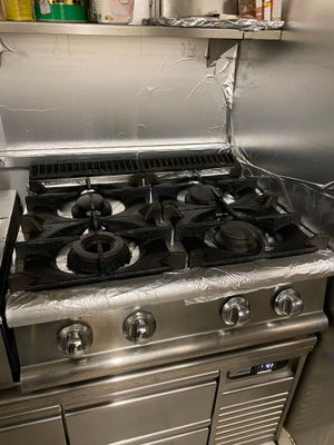 une cuisinière en acier inoxydable dans une cuisine dotée de nombreux plans de travail