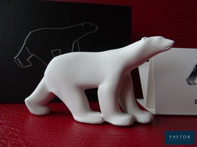 une petite figurine d'ours polaire blanc posée à côté d'une boîte