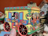 a hand holding a small toy train with people on it