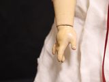 a doll that is wearing a white dress and a red tie