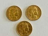 three gold sovereigns on a white surface with a white background