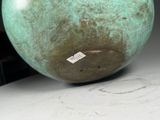 a green vase sitting on a table with a tag on it