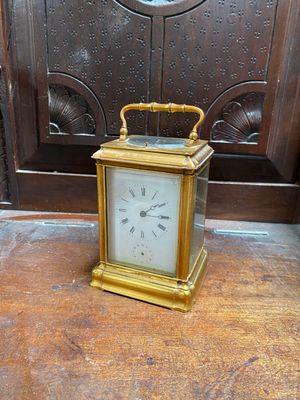 une horloge en or posée sur une table en bois devant une porte