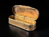 a small gold box with a handle on a black surface