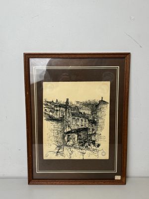 dessin représentant un paysage urbain, encadré dans un cadre en bois et accroché à un mur blanc