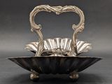 an antique silver plate with a heart shaped handle on a stand