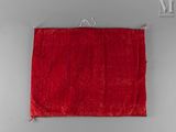 an old red cloth hanging on a wall with a metal hook