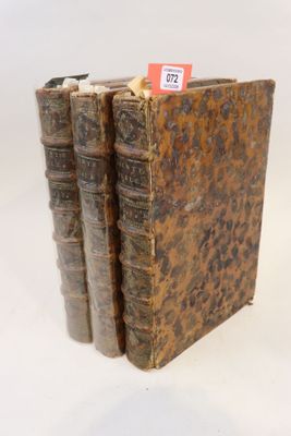trois vieux livres sont empilés sur une surface blanche
