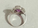 an image of a ring with a purple stone in it on a table