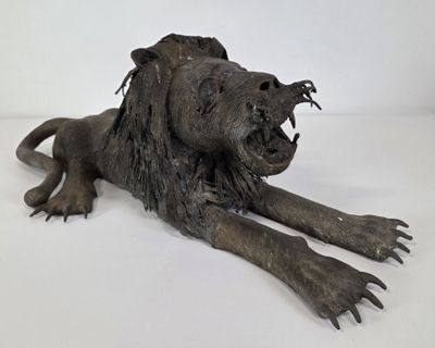 statue of a lion laying on its side with its mouth open