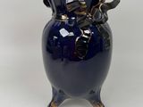 a blue vase that has a gold handle on it