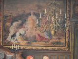 a painting on the wall of a room with a woman sitting at a table
