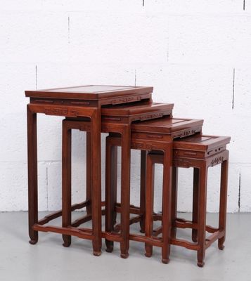 un ensemble de trois tables gigognes en bois posées sur un sol en ciment