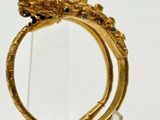 un gros plan d'une bague en or ornée d'une tête de dragon