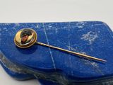 une photo d'une broche fixée à une épingle de revers posée sur une boîte bleue